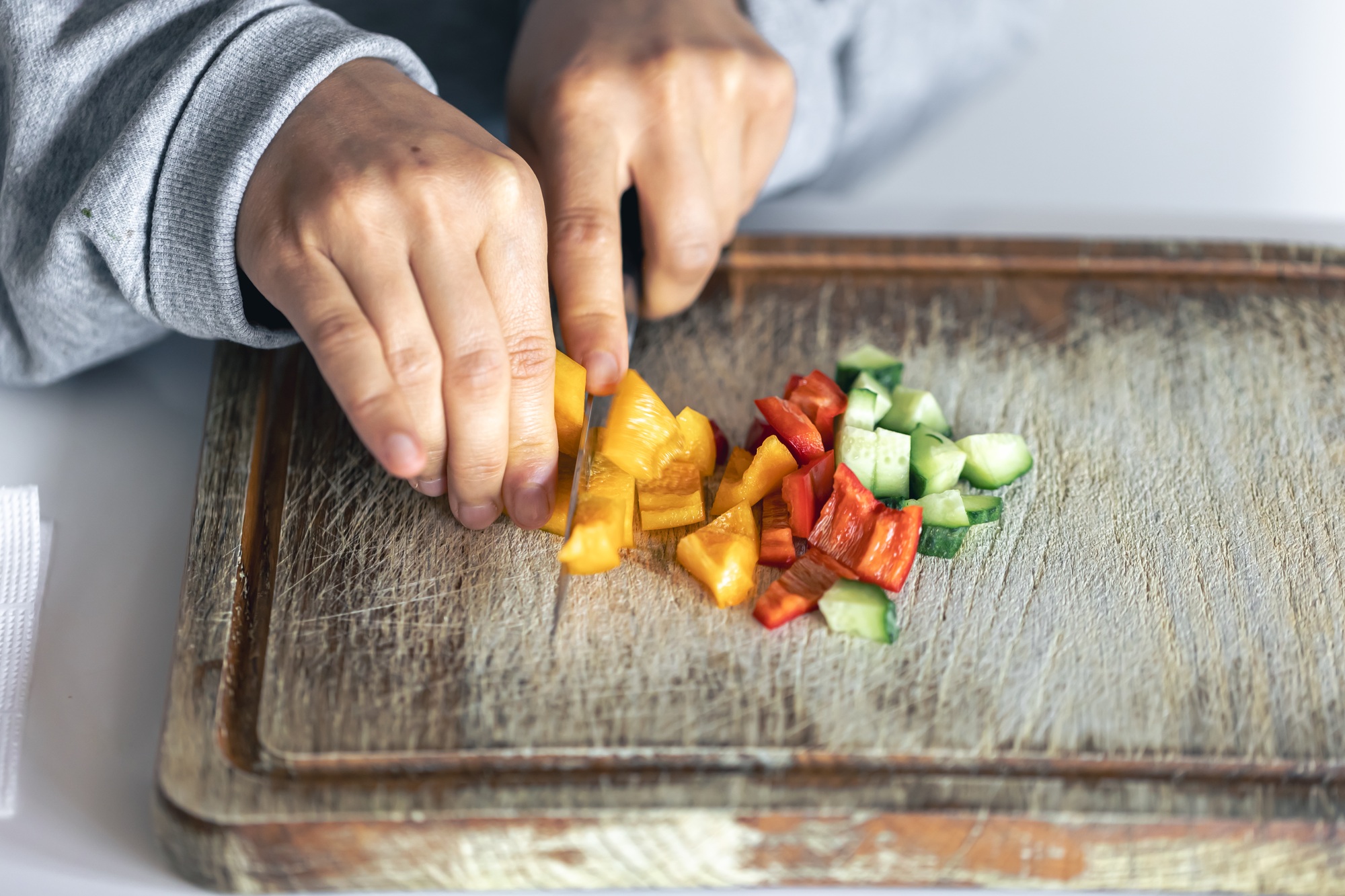 A woman cuts vegetables on a cutting board.